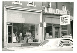 Store front view of a Woman's Place library or resource centre with two women consulting books in...
