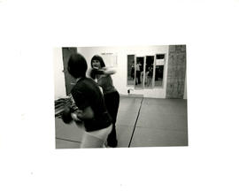 Back view of two women practicing boxing with mirrors in the background at the Amazon Self-Defenc...