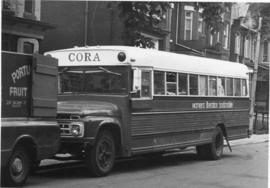 CORA Bookmobile parked in a street behind fruit produce truck