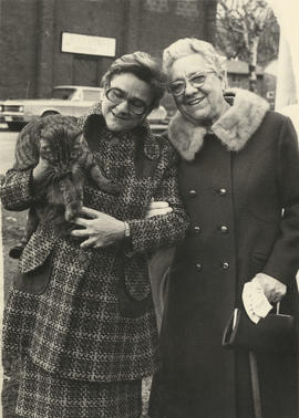 Two unidentified women standing in the street with one holding a cat