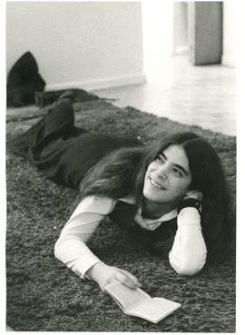 Woman lying on carpet holding a small book