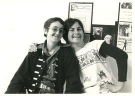 Photo of [Scamp?] and Lynn Kirk in front of a notice board